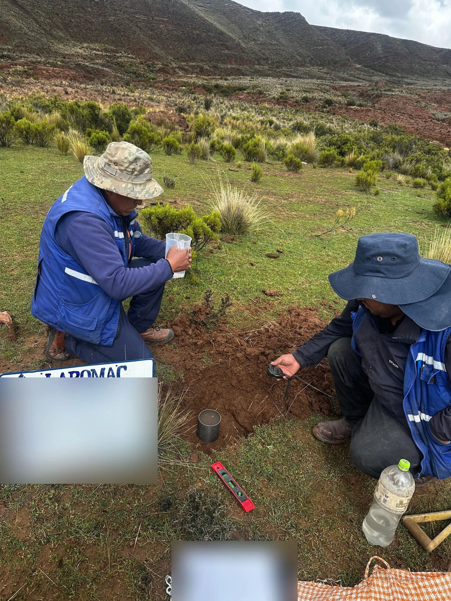 Dos técnicos realizando un ensayo de permeabilidad en un terreno con pasto, en el altiplano.