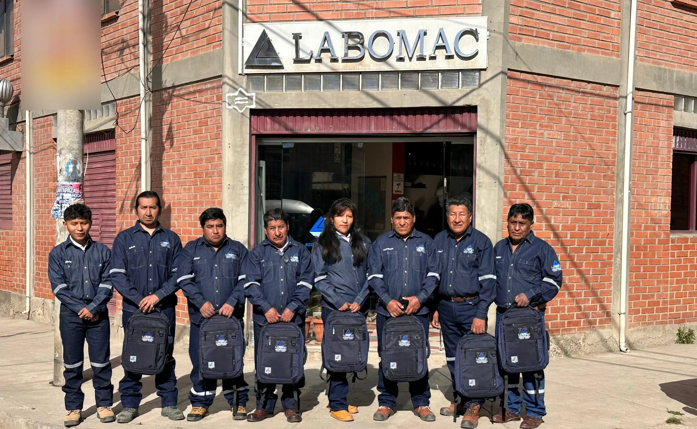 Ocho integrantes del equipo de LABOMAC, con uniforme azul, frente a la fachada del laboratorio.