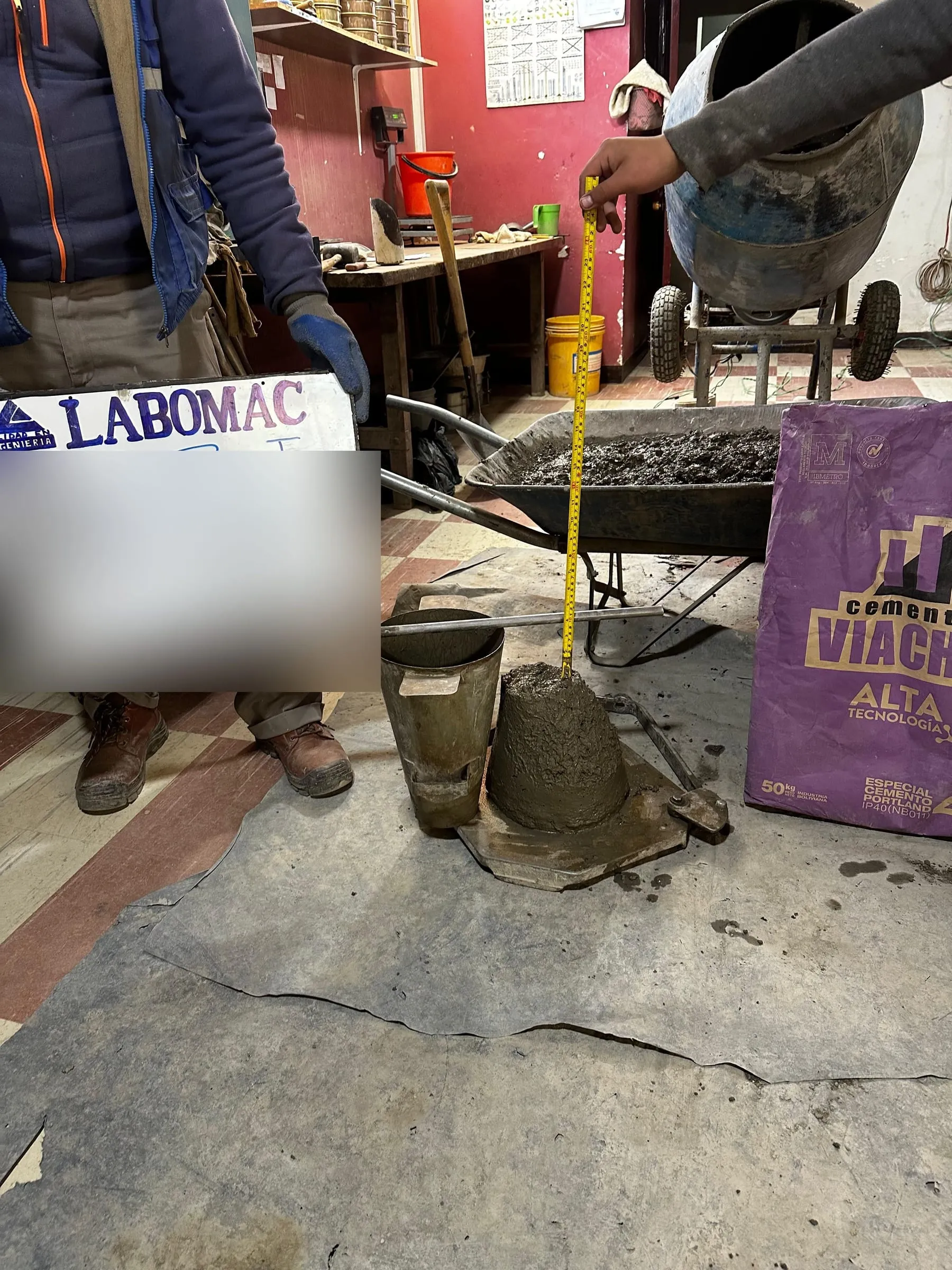Medición del asentamiento de una mezcla de hormigón con el cono de Abrams y una cinta métrica.